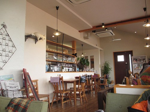 cafe 風車の丘の店内。カウンターと木のテーブル席、手前に緑のソファ