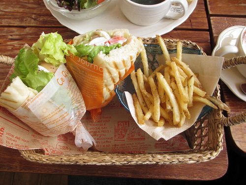 かごに入ったサンドイッチのセット。紙に包まれたサンドとポテトフライ