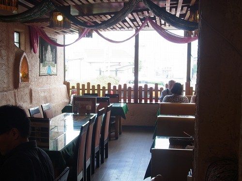 カーナピーナの店内。天井から赤と緑の布が垂れ、窓ぎわにテーブル席が並んでいる