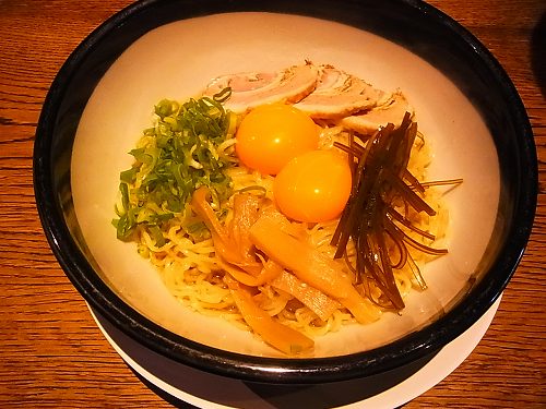 釜たまラーメン。スープのない麺の上に卵の黄身が二つ、チャーシュー、ねぎ、メンマ、細切りの昆布がのっている